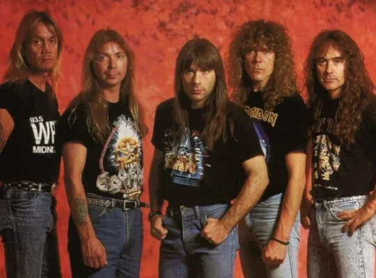 Archiwalne grupowe zdjęcie pięciu długowłosych muzyków rockowych na czerwonym tle. Bez dodanego napisu.